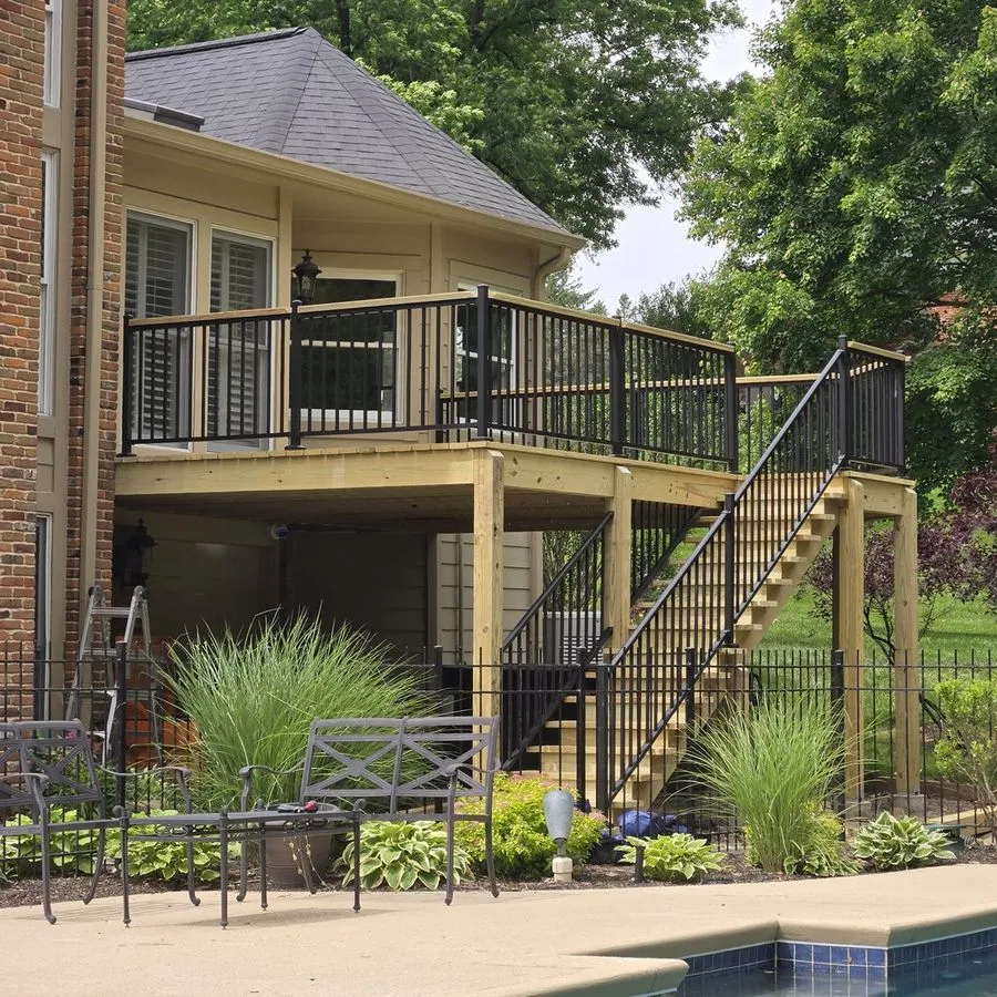 Elevated custom deck with black railings and staircase overlooking a pool